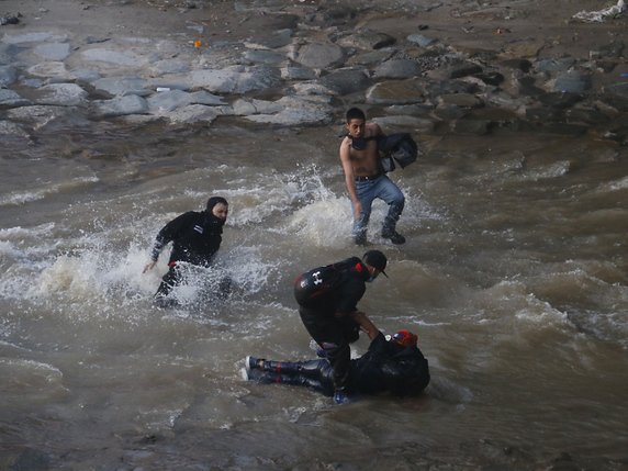 Des manifestants sont venus en aide au jeune homme qui est tombé dans le fleuve Mapocho. Il a ensuite été pris en charge par des médecins et des pompiers et héliporté à l'hôpital. © KEYSTONE/EPA/Sebastian Silva