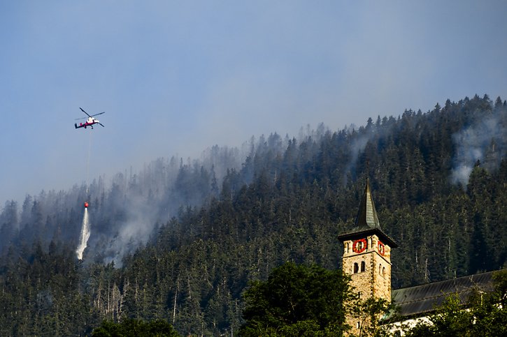 Les opérations d'extinction étaient encore en cours mardi matin au-dessus des villages de Bitsch et Ried-Mörel, dans le Haut-Valais. © KEYSTONE/JEAN-CHRISTOPHE BOTT